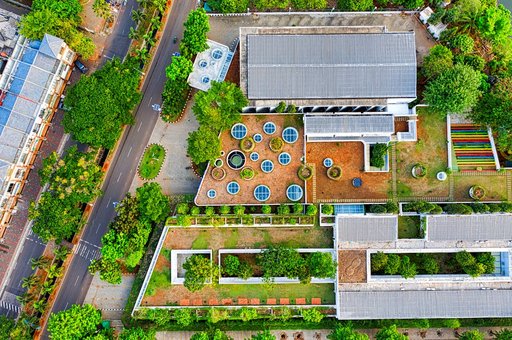 Tampilan udara sebuah bangunan besar yang dikelilingi oleh taman hijau, menampilkan kehijauan dan desain arsitektur