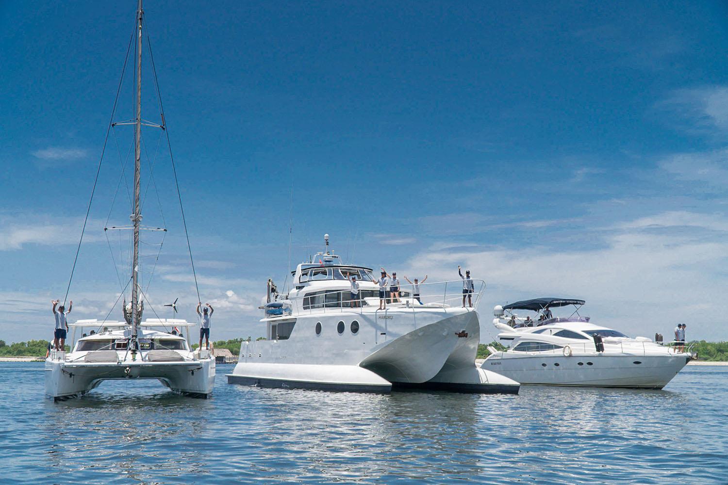 Three boats are docked peacefully in the water, inviting you to charter a private yacht in Bali.