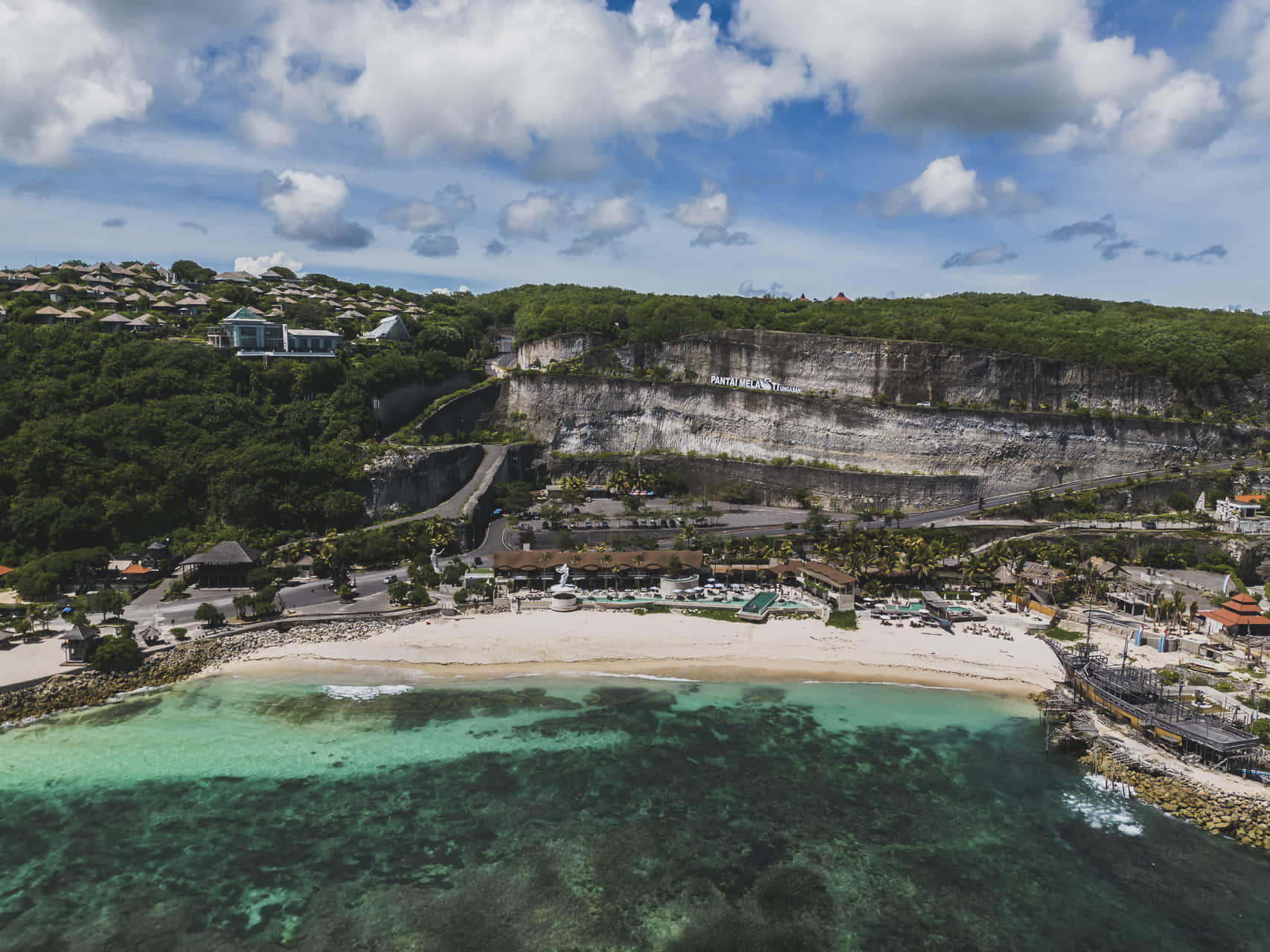 Scenic view of Bali's beach with turquoise waters and towering cliffs under a clear blue sky