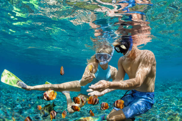 couple snorkeling with fishes